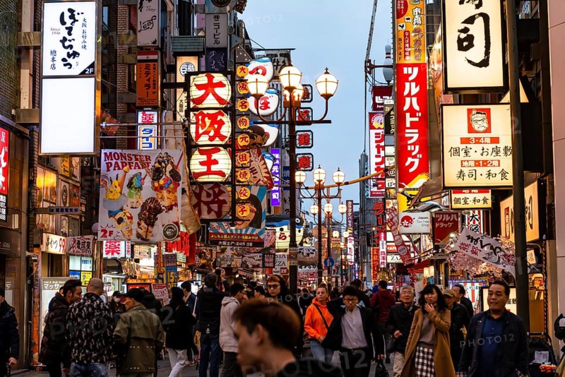 Crowd crowded in pedestrian zone with lots of illuminated advertising for restaurants and shopping centers