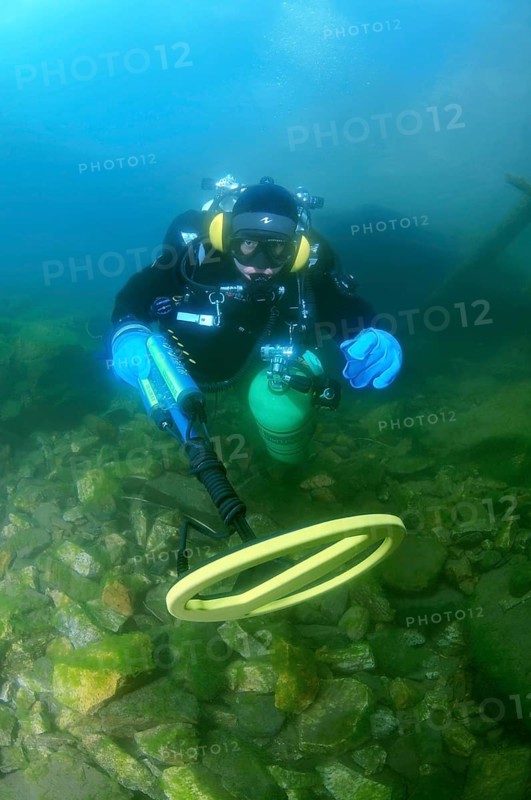 Diver with metal detector searching for underwater treasure