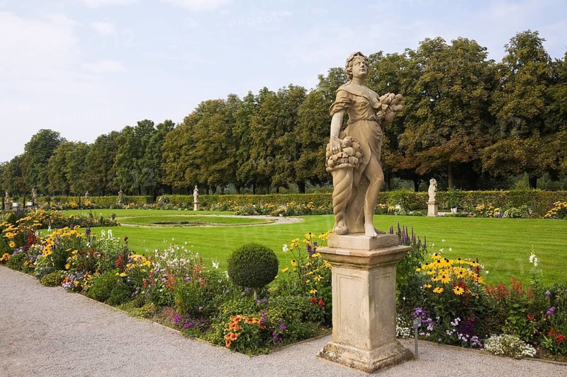 Statue and border with flowers and manicured lawn in the grounds of Schloss Weikersheim Palace garden in late summer