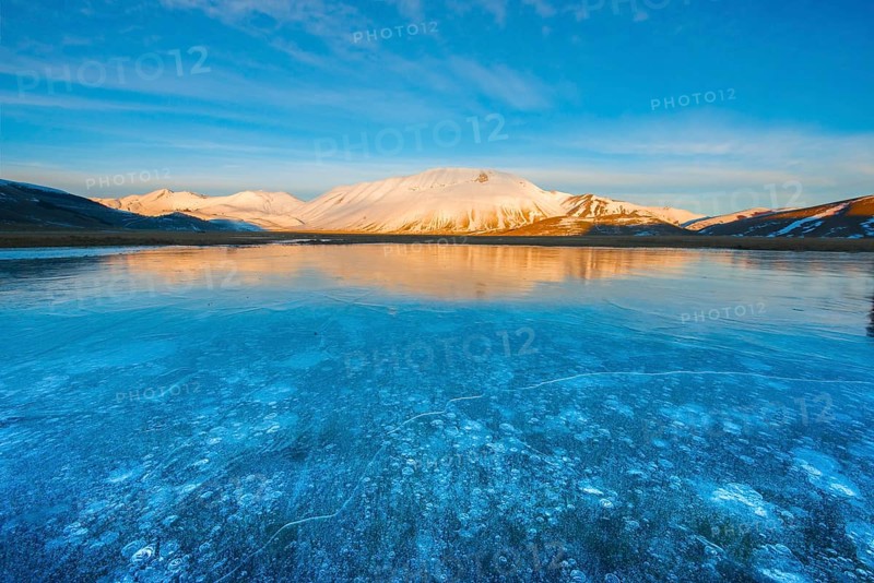 Monte Vettore in the evening light with a frozen puddle with air bubbles
