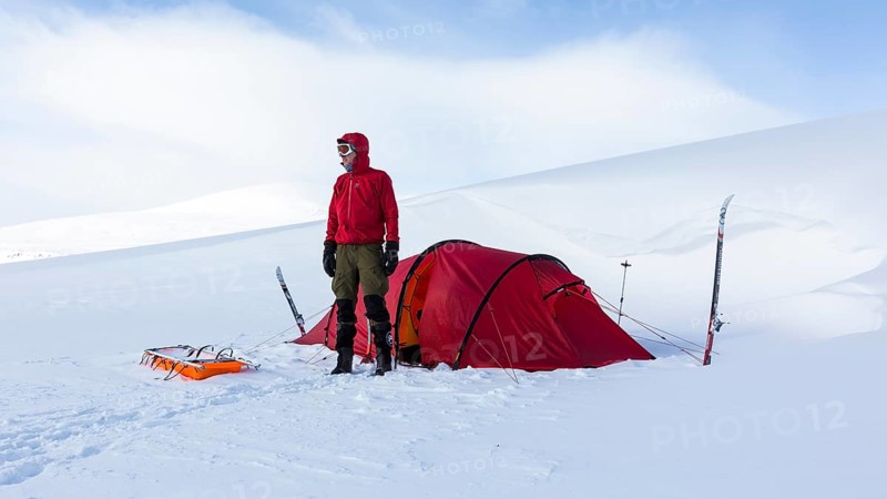 Ski tourer with tent in the snow