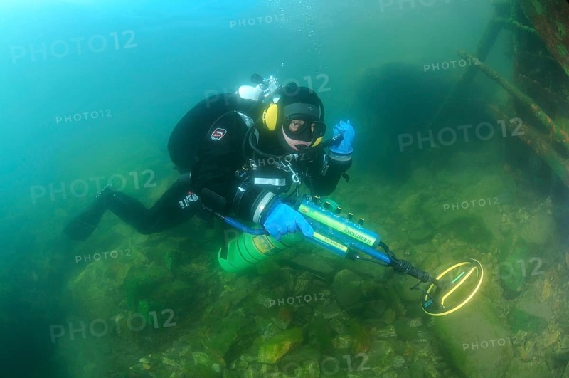 Diver with metal detector searching for underwater treasure