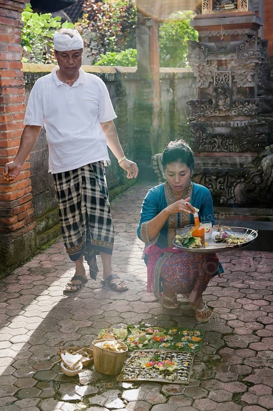A woman during the daily ceremony of sacrificial offerings in front of a house