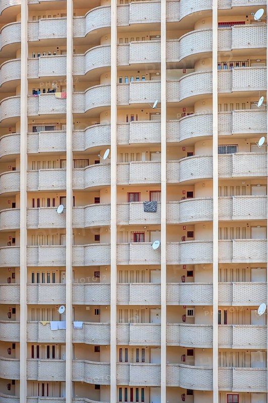Facade of a skyscraper with satellite dishes on balconies