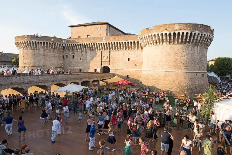 People dancing in the festival grounds in front of Fortress Rocca Roveresca