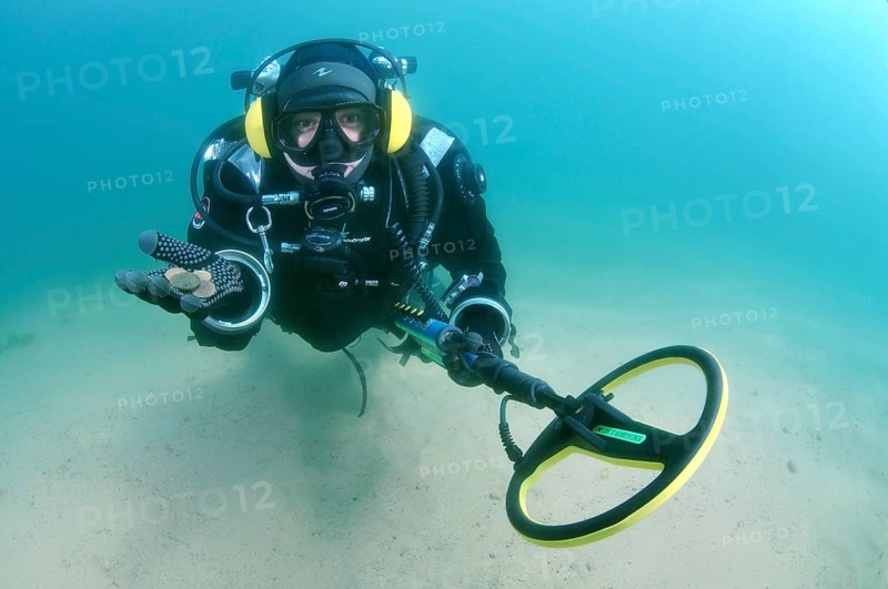 Diver with metal detector displays the ancient coins he found