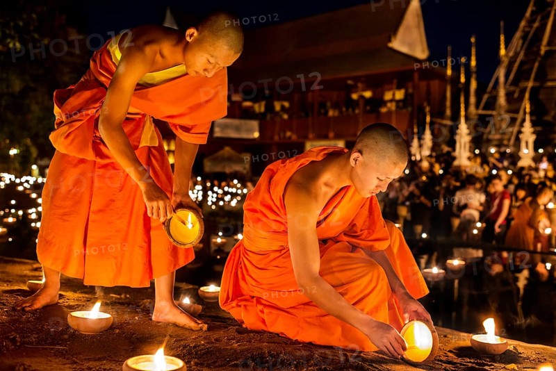 Young monks lighting candles during the Macha Pucha celebration at Wat Pan Tao
