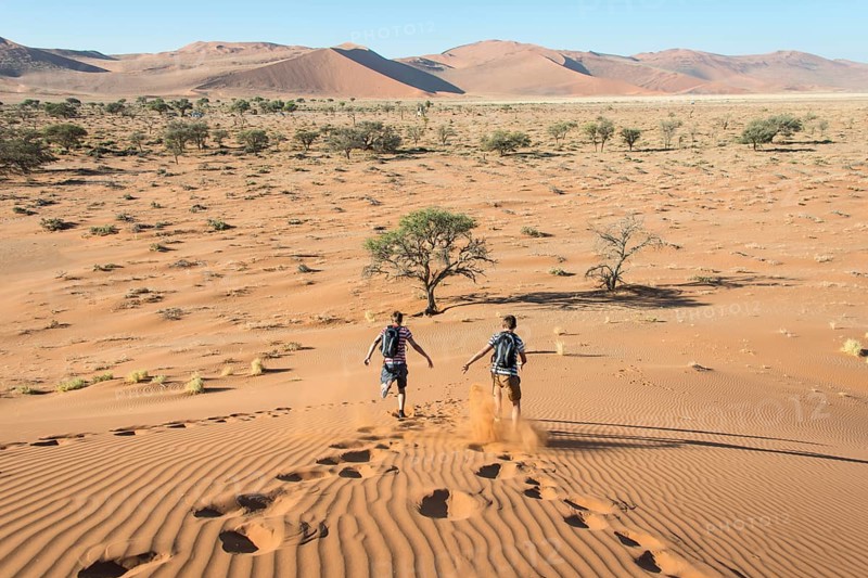 Two teens running down a dune
