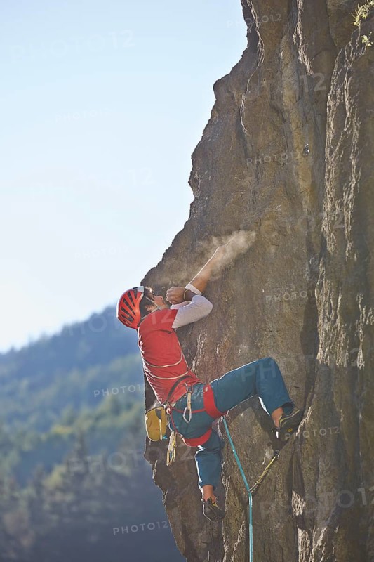 Sport climber wearing a helmet climbing a rock face