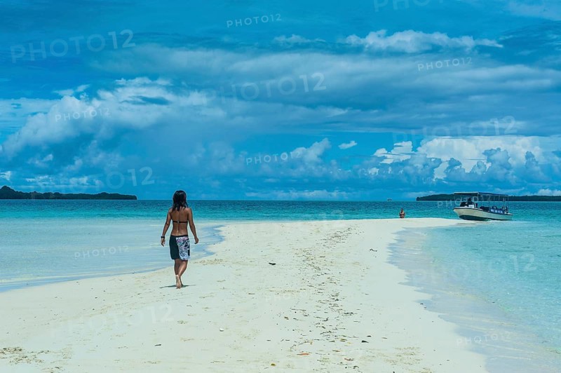 Tourist walking on a sand strip at low tide