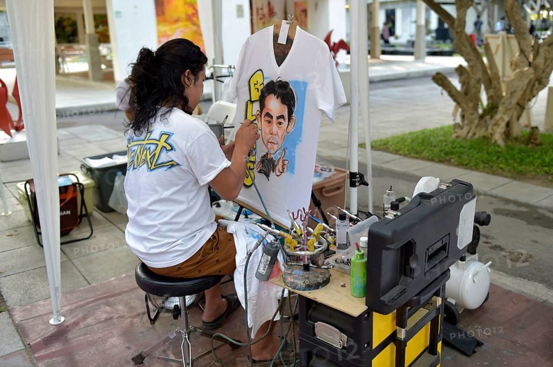 Woman airbrushing a portrait on a T-shirt