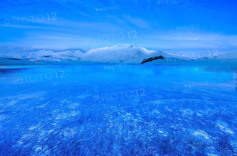 Monte Vettore at blue hour with a frozen puddle with air bubbles