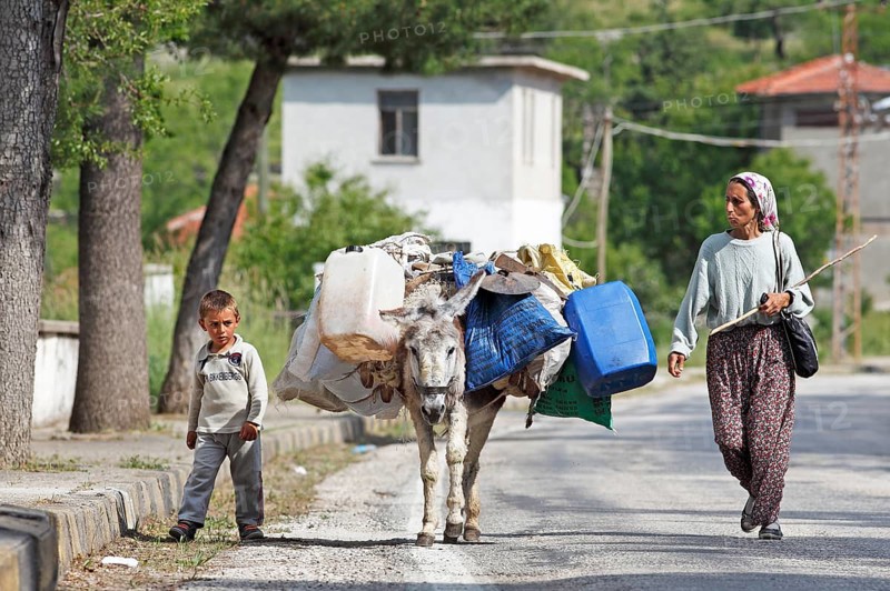 Woman and boy with donkey walking along a mountain road