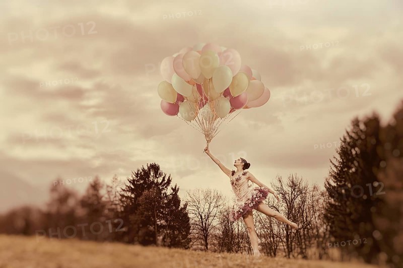 Young woman holding lots of balloons