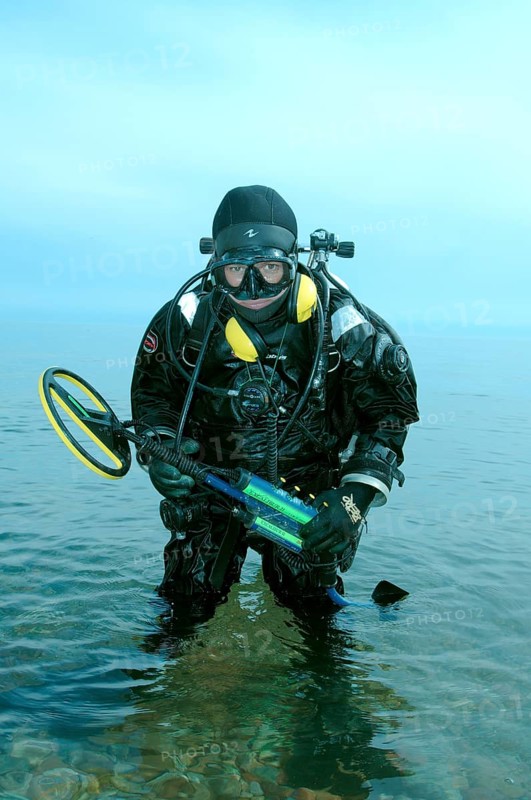 Diver with metal detector searching for underwater treasure
