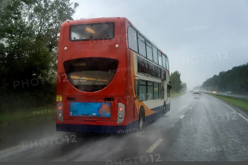 Red bus in the rain on the highway