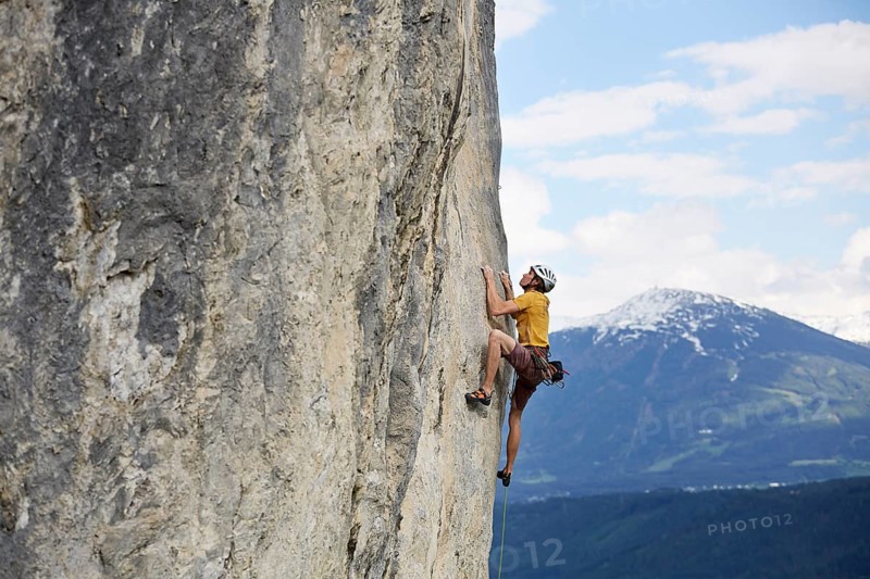 Freeclimber with helmet climbing on a rock face