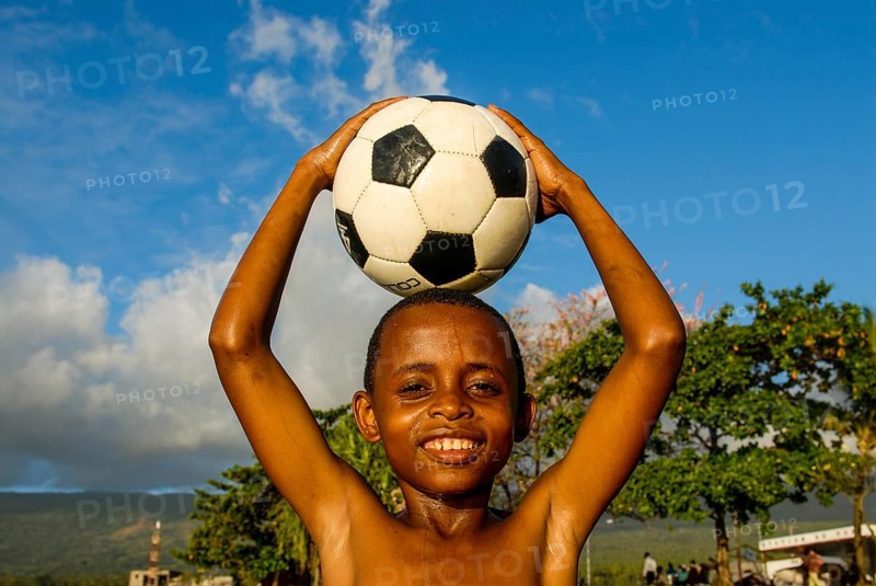 Smiling boy holding a football on his head