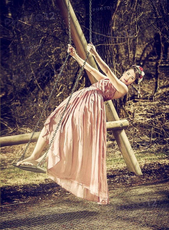 Young woman with flowers in her hair standing on a swing