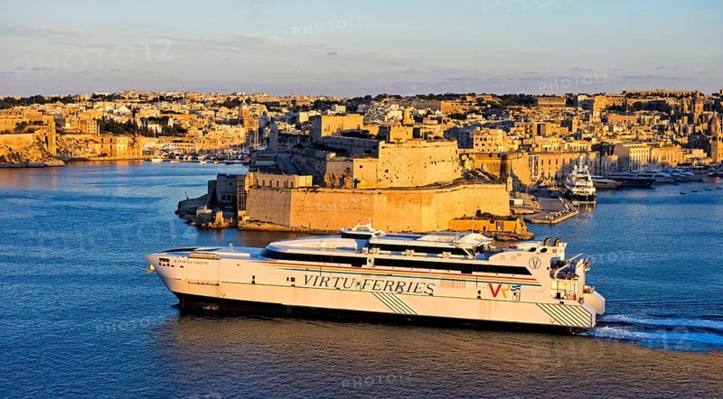 Jean de la Valette ferry of the Virtu Ferries shipping company passing the fortress Fort St. Angelo in the Grand Harbour