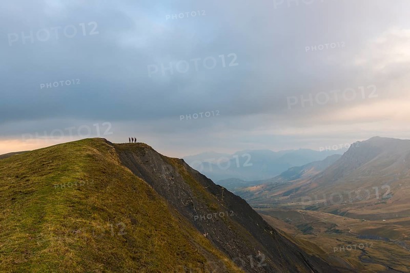 Three hikers on the ridge of a mountain in the Ecrins at dusk