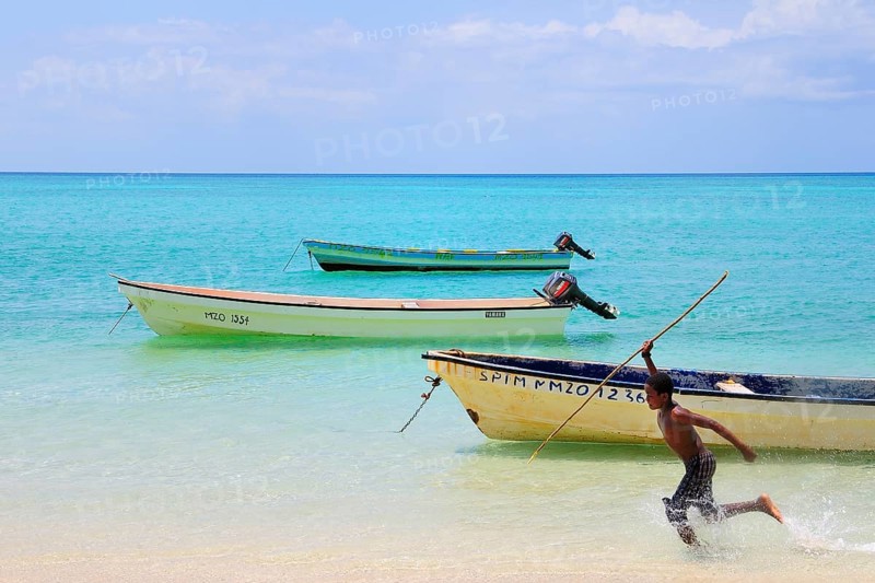 Boy with spear chasing fish in the shallow water