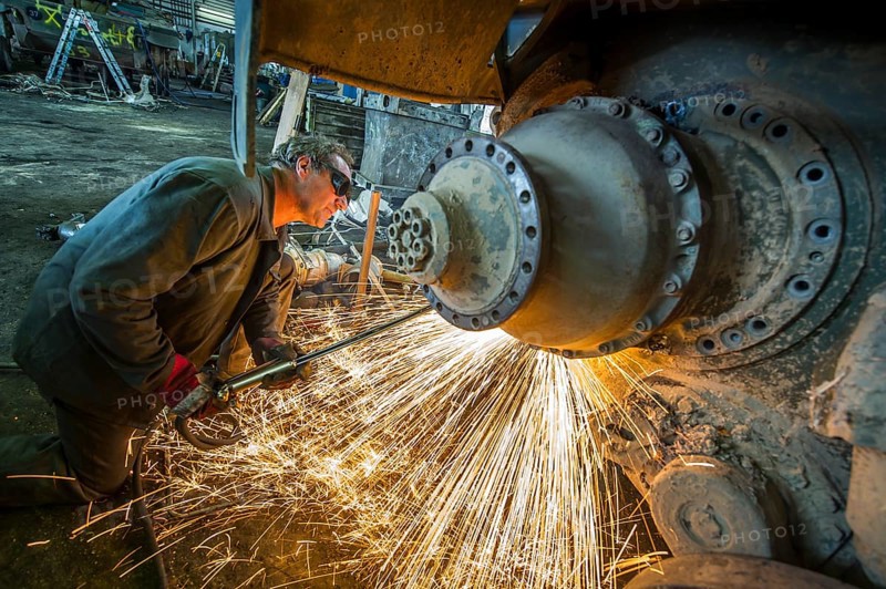 A man cutting up an armored vehicle type Marder with a torch