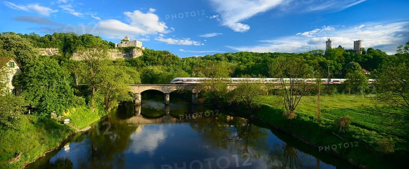 Ruins of Rudelsburg Castle and Burg Saaleck Castle on the Saale River with an ICE train crossing a railway bridge