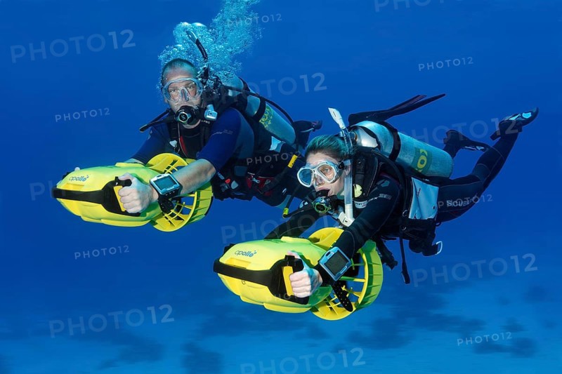 Divers with diver propulsion vehicles exploring a coral reef