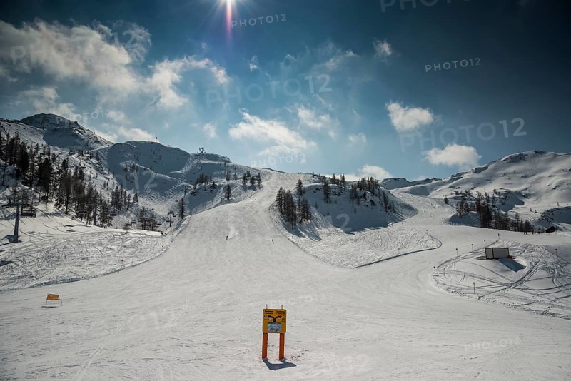 Ski slope with signposts and a few skiers on Gamskogel