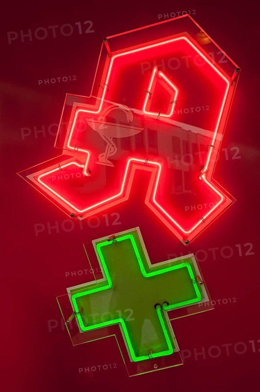 Neon sign of a pharmacy with a green cross