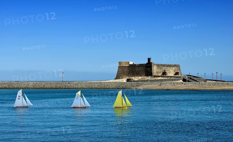 Model sailing boats in a regatta in front of the fort Castillo de San Gabriel