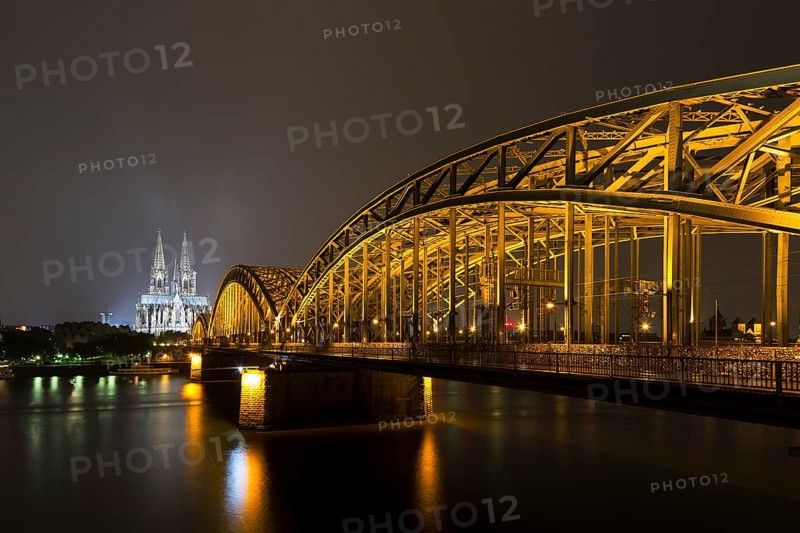 The illuminated Cologne Cathedral and Hohenzollern Bridge at night with Rhine