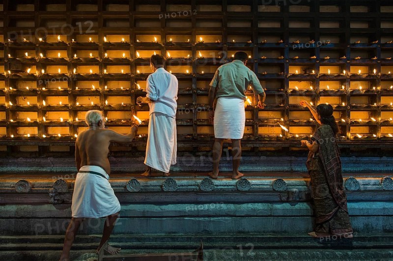 Oil lamps being lit in niches on the outer wall of the temple for the Hindu fire ceremony Aarti