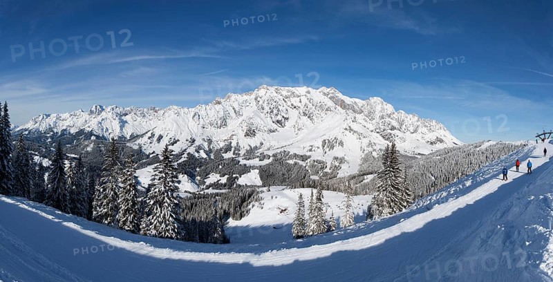 Skiers on ski slope in front of mountain scenery