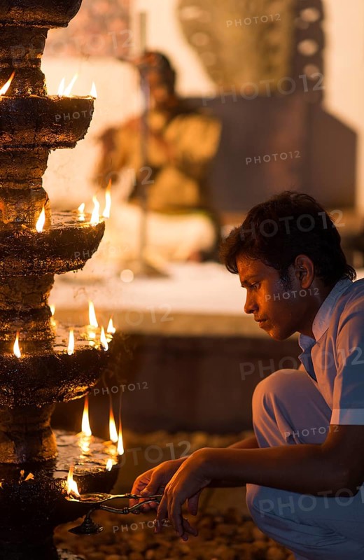 Young man lighting oil-soaked wicks on a stone chandelier