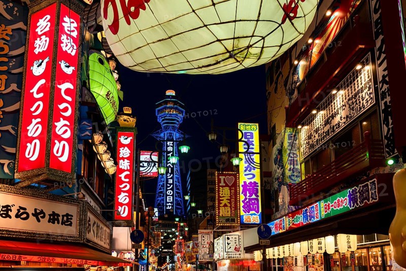 Many colorful neon signs in a pedestrian zone with shops and restaurants