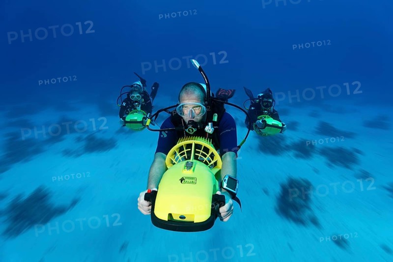 Divers with diver propulsion vehicles exploring a coral reef