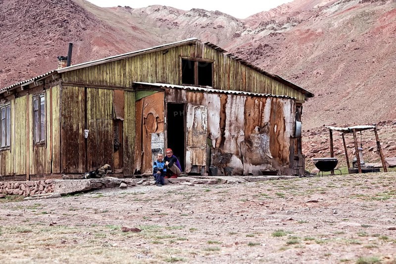 People sitting outside a delapidated hut