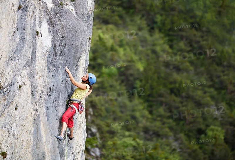 Freeclimber with helmet climbing on a rock face