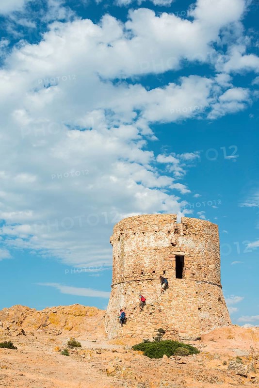 Three people walking down from a Genoese tower