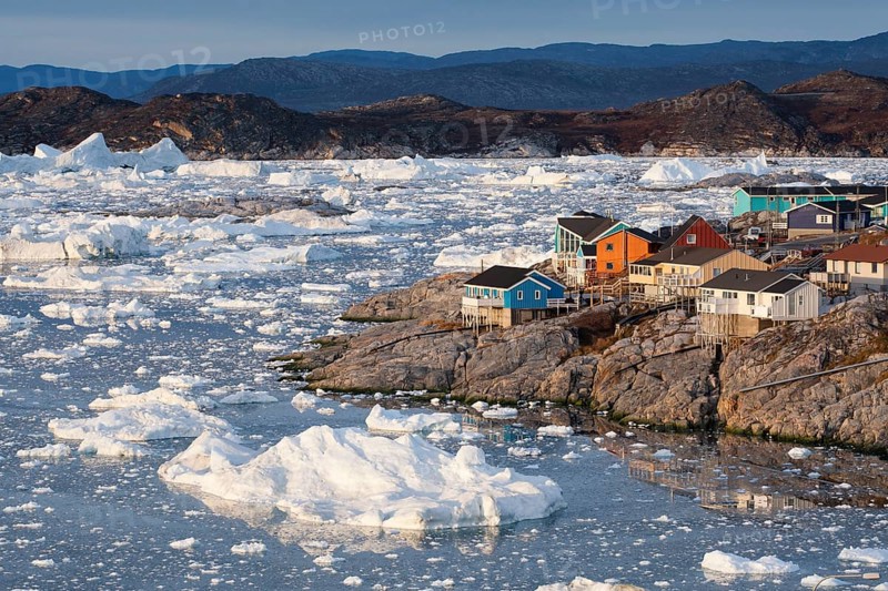 Colourful timber houses by the sea with iceberg fragments