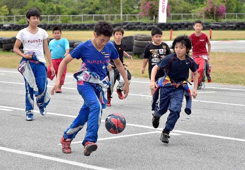 Teenager in racing overalls playing football