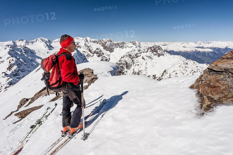 Ski tourer on the summit ridge with overhanging snow