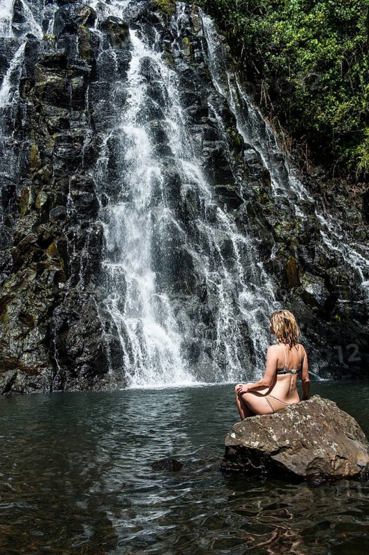 Woman sitting in front of the Kepirohi waterfall