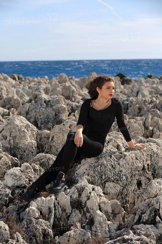 Teenager sitting on rocks by the sea