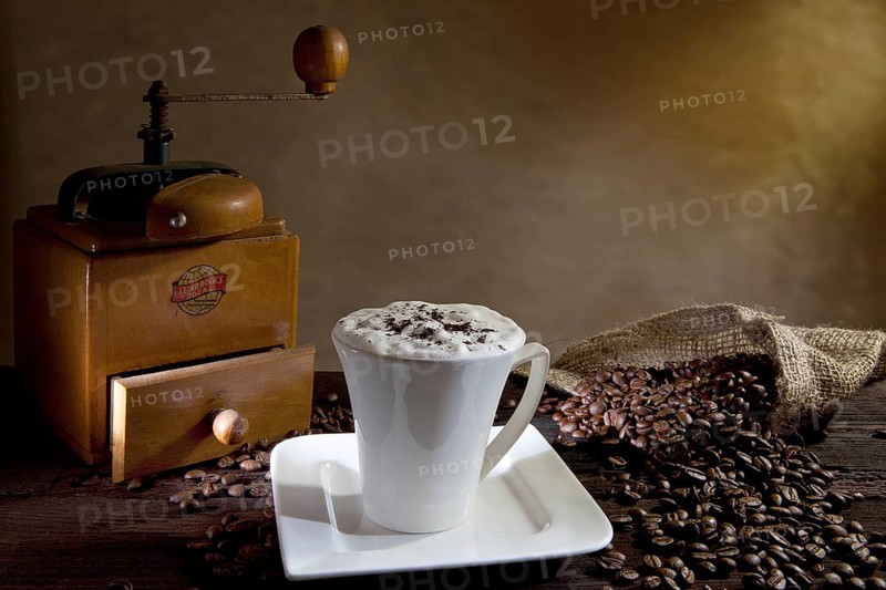 Cup of cappuccino with coffee beans and an old coffee grinder