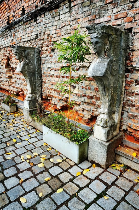 Stone sculptures and bamboo in front of a brick wall