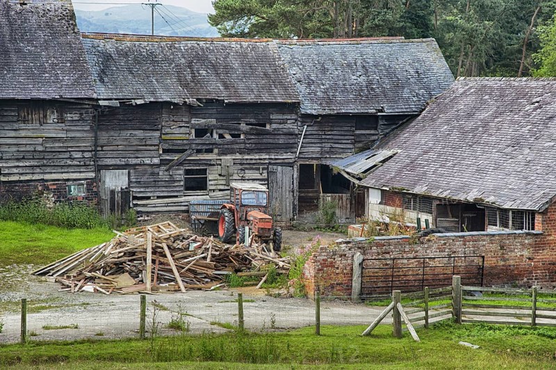 Derelict farmyard with old farm buildings and tractor