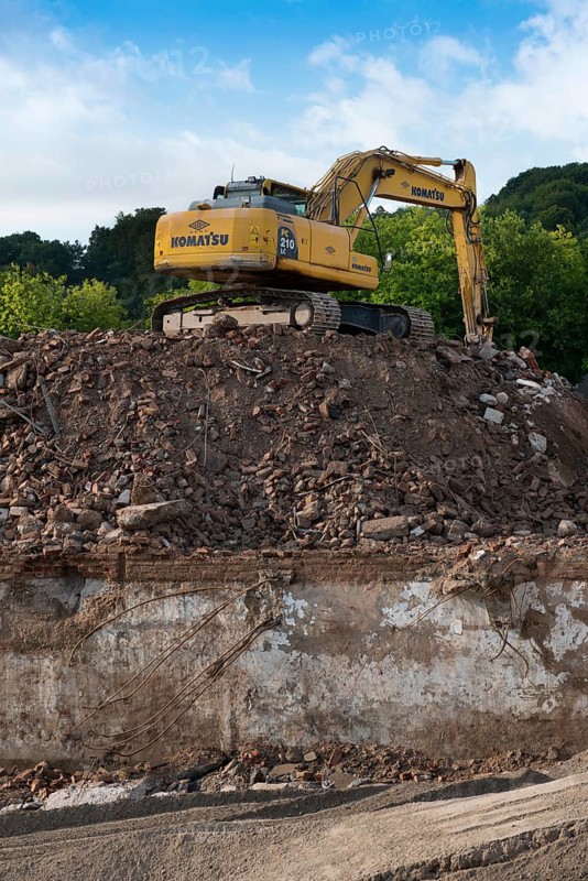 Excavator standing on a large rubble heap